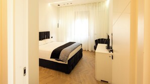 Une chambre d’hôtel moderne avec un grand lit, une table de chevet et un petit meuble.