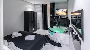 A modern bedroom with a bed, a large mirror, a TV, and a bathtub. - Amour (Rosolini)