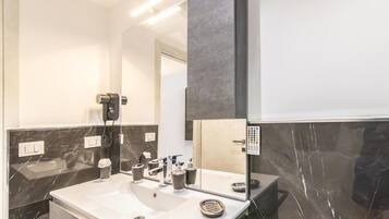 A modern bathroom with a large mirror, a white sink, and a black marble backsplash.