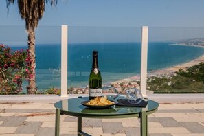 A table with a bottle of Ferrari wine, a glass, and a plate of snacks, overlooking a coastal view. - Miramare Suites - Camera Azzurra (Vasto)