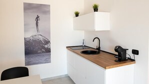 Moderni keittiö, jossa on puinen työtaso, musta pesuallas ja pieni ruukkukasvi seinällä.