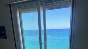 A room with a sliding glass door leading to a balcony with a view of the sea. - Perla Sul Mare (Vibo Marina)