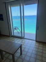 Quarto com porta de vidro deslizante que dá para uma varanda com vista para o mar.
