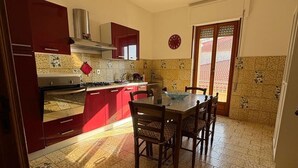 A kitchen with a dining area, a ceiling fan, and a clock on the wall. - Perla Sul Mare (Vibo Marina)