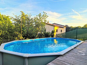An above-ground swimming pool with a wooden deck, surrounded by trees and a house. - Ca di Borra - Orto Bio e Piscina (Badia Tedalda)