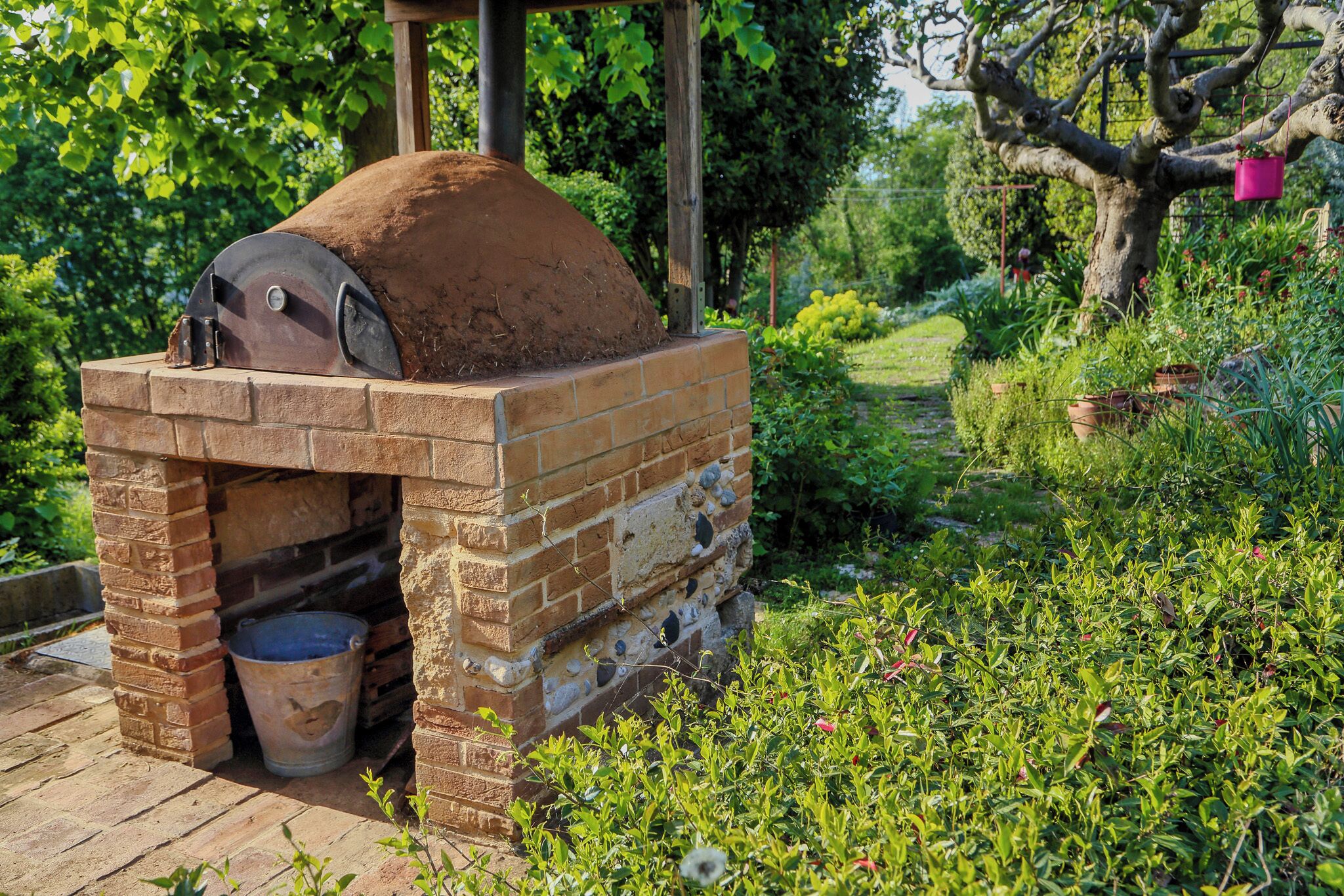 A brick-built outdoor oven in a garden setting.