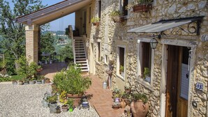 A stone building with a covered patio, outdoor seating, and potted plants. - Casa in Bioedilizia con Bio Piscina Naturale – Ai Due Gelsi (Val Liona)