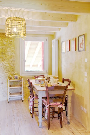 A dining area with a wooden table, chairs, and a hanging light fixture. - Casa in Bioedilizia con Bio Piscina Naturale – Ai Due Gelsi (Val Liona)