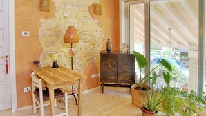 A room with a wooden table, chairs, a lamp, a cabinet with artwork, and potted plants. - Casa in Bioedilizia con Bio Piscina Naturale – Ai Due Gelsi (Val Liona)
