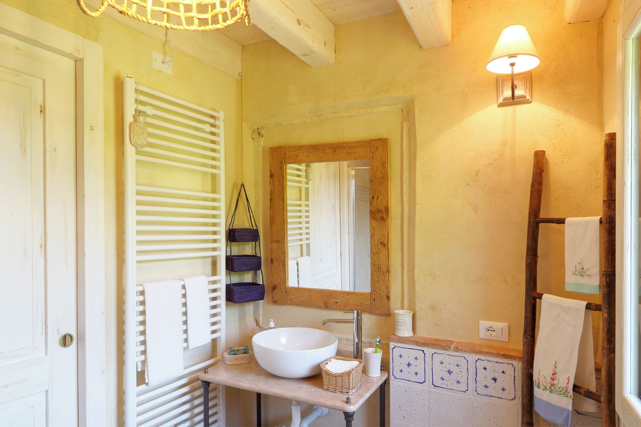 A bathroom with a white sink, wooden towel rack, and a mirror with a wooden frame.