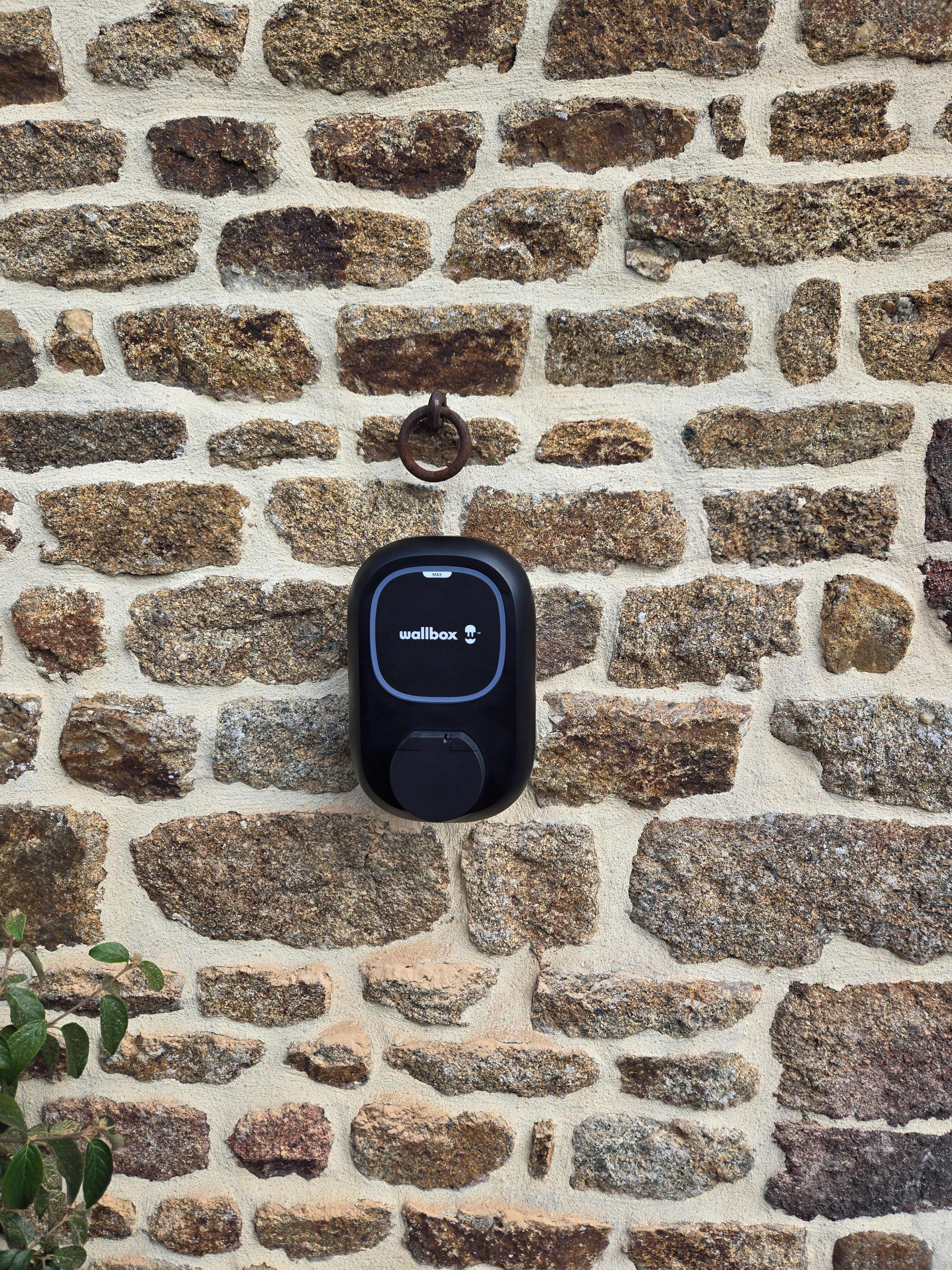 Un appareil fixé au mur, doté d’un clavier et d’un écran, vraisemblablement un système de sécurité ou de contrôle d’accès, installé sur un mur en pierre.
