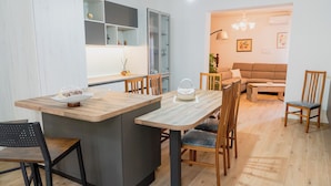 A modern kitchen with a central island, wooden chairs, and a dining table.