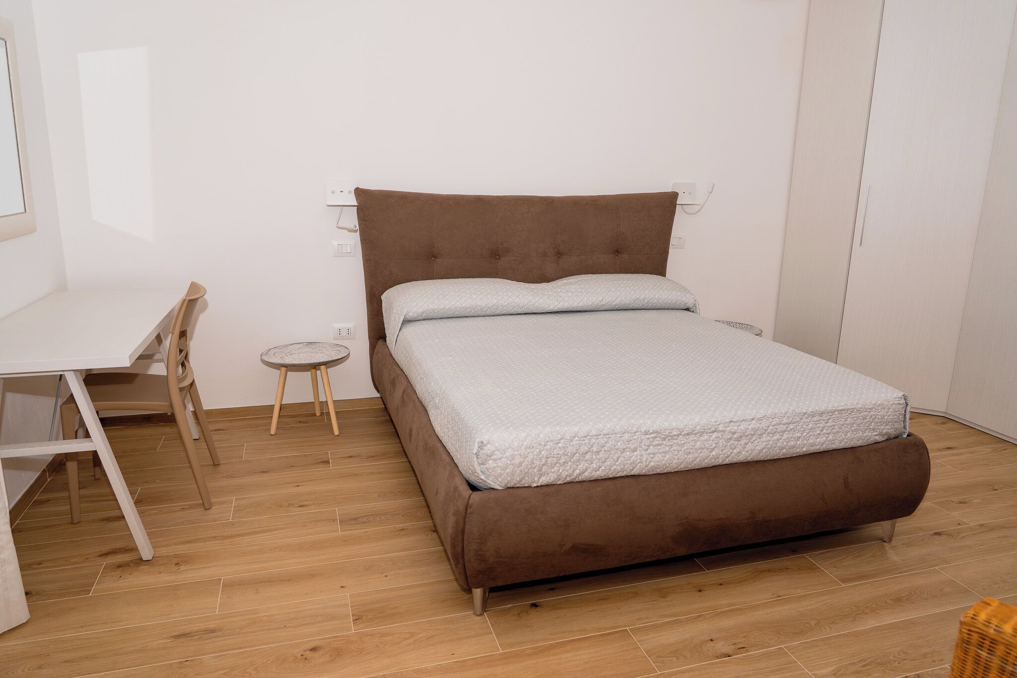 A bedroom with a bed, a desk, and a chair.