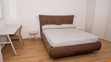 A bedroom with a bed, a desk, and a chair.