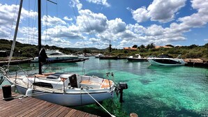 A marina with several boats docked, clear turquoise water, and a wooden dock. - Casa A.Danieli (Olbia)