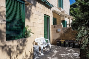 A building with green shutters, a bench, and recycling bins. - Casa Onda (Maruggio)