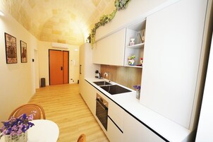 Una cucina moderna con mobili bianchi, un piano di lavoro nero e un pavimento in legno.