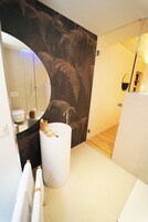 Un bagno moderno con uno specchio grande, una vasca da bagno indipendente e uno scaffale in legno.