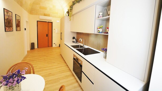 Eine moderne Küche mit weißen Schränken, einer schwarzen Arbeitsplatte und Holzboden.