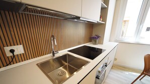 Eine moderne Küche mit Spüle aus Edelstahl, einer Wandpaneele aus Holz und einem Fenster für natürliches Licht.