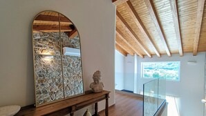 A wooden bench with a stone mosaic wall and a bust sculpture.