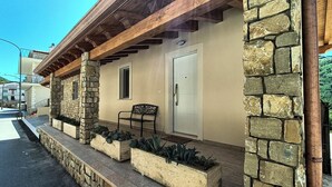 A stone exterior with a wooden porch, a door, and a bench.