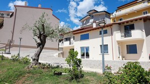 A residential building with a balcony, a tree, and a clear blue sky.