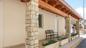 A stone pillar, a bench, and planters on a building's exterior.
