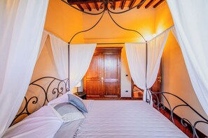 A bedroom with a canopy bed, wooden door, and a small bedside table. - Holiday Home Croce (Lucignano)