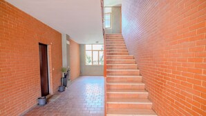 A spacious corridor with brick walls, a tiled floor, and a staircase leading to an upper level. - San Giacomo Sweet Home (Nettuno)
