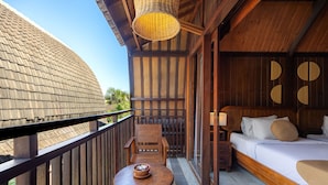 Un balcon avec une table et des chaises en bois, un lit avec des oreillers et un luminaire suspendu.