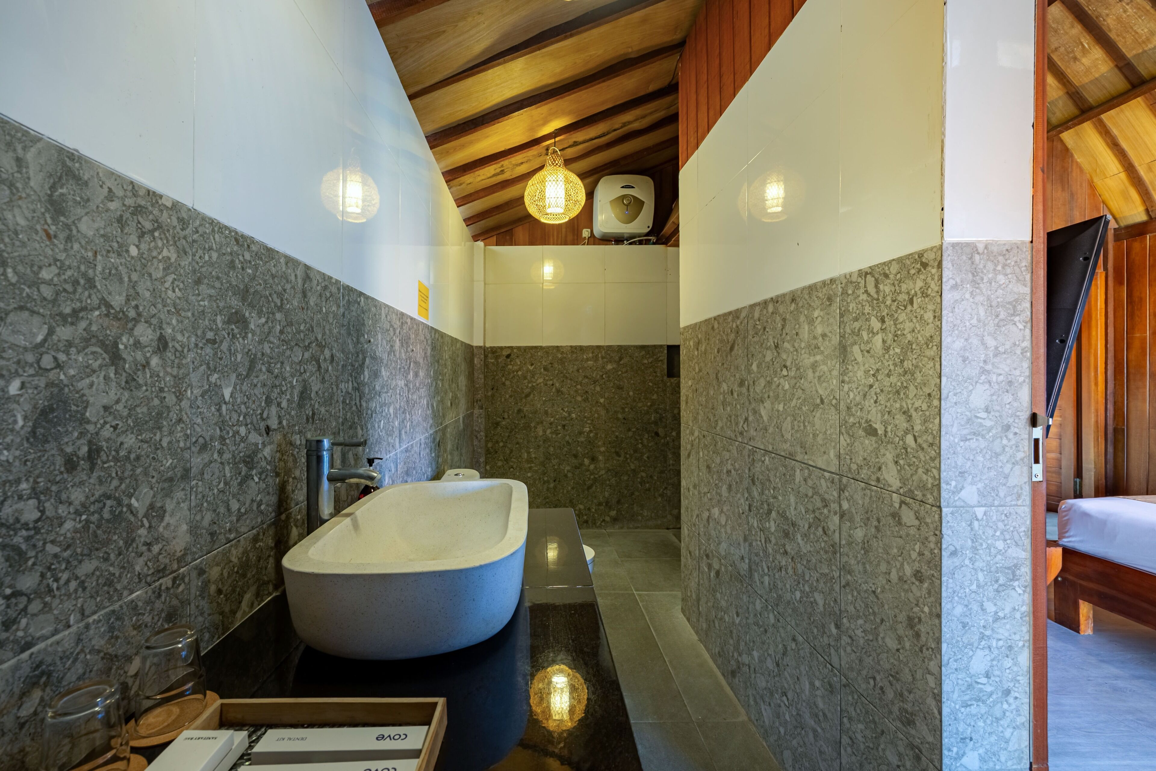 A modern bathroom with a freestanding bathtub, marble walls, wooden ceiling beams, and a built-in toilet.
