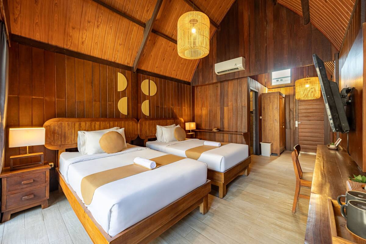 A wooden room with two beds, a dining table, and a television.