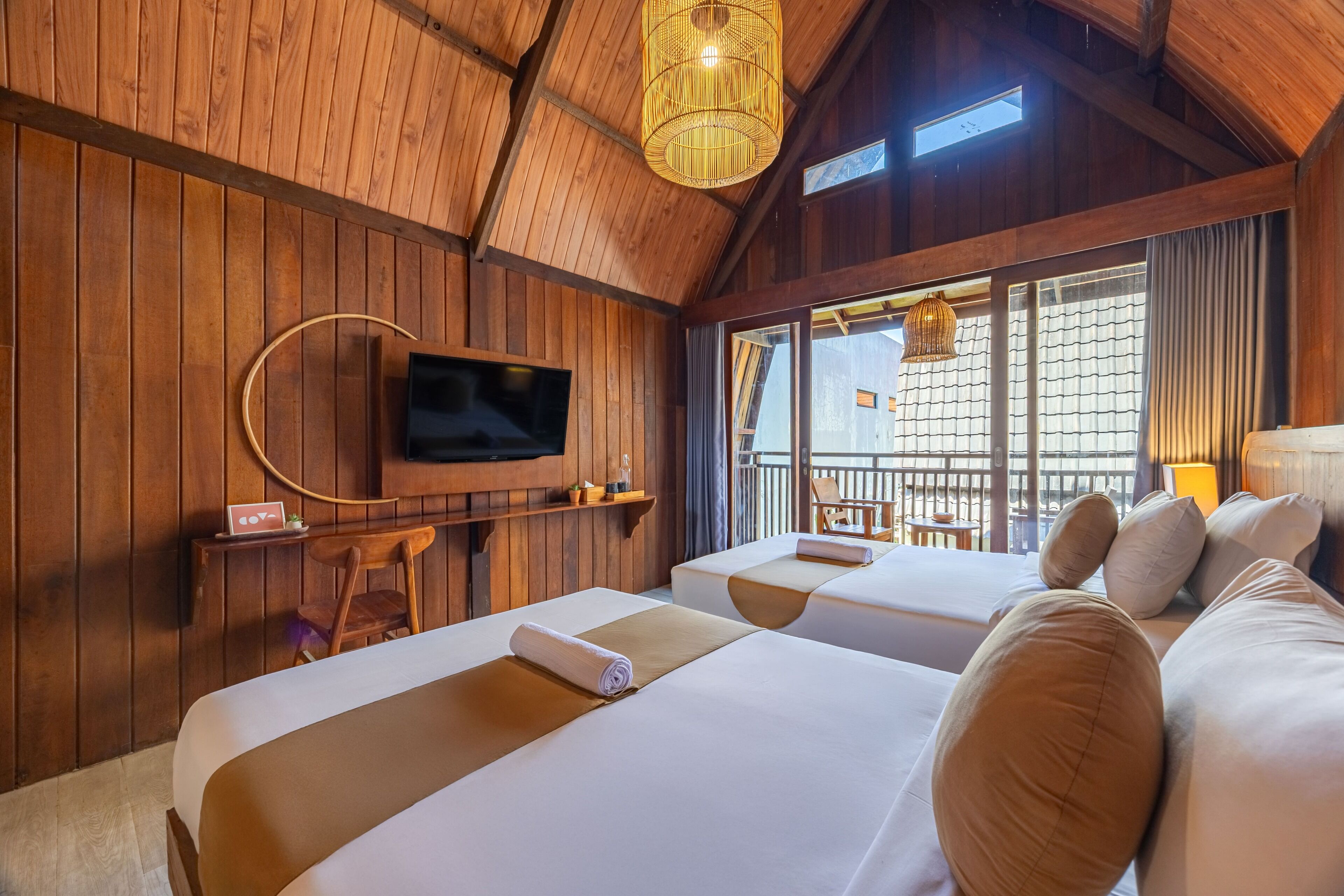 Ein Zimmer aus Holz mit zwei Betten, einem Fernseher und einem Balkon mit Blick.
