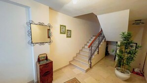 Eine Treppe mit hölzernem Geländer und weißen Stufen, die zu einer oberen Etage führt.