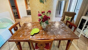 Ein Essbereich mit einem Holztisch, Stühlen, einer Vase mit roten Rosen und einer gefliesten Rückwand.