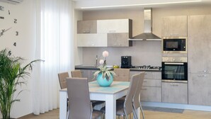 A modern kitchen with built-in appliances, a dining area with a table and chairs, and a potted plant. - Casa Vacanze Stella Marina (Marina di Palma)