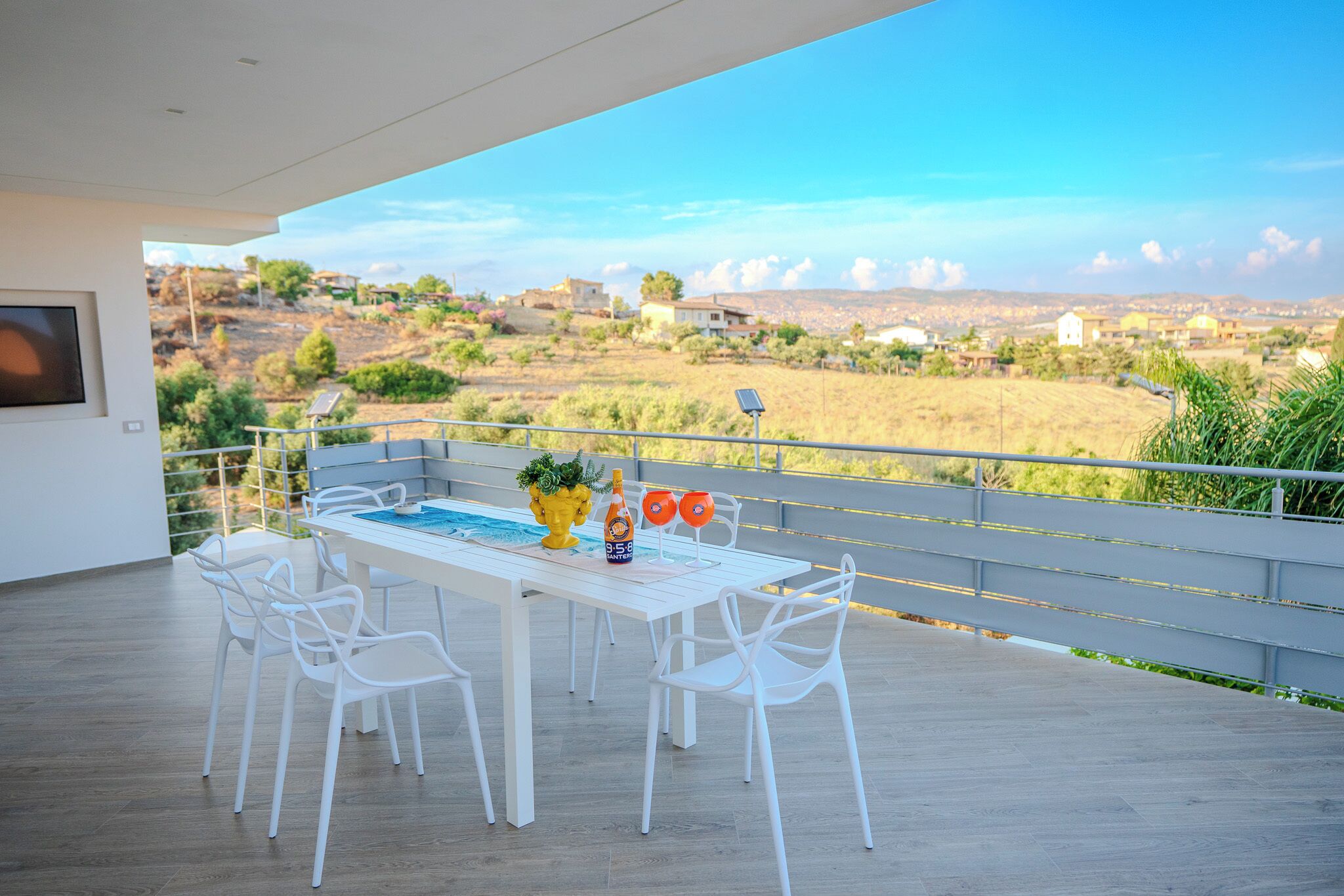 A modern outdoor dining area with a pool table, white chairs, and a scenic view of a rural landscape.