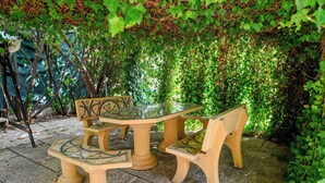 A stone table and bench set in a garden with a green leafy backdrop. - Villa Leproso (Benevento)