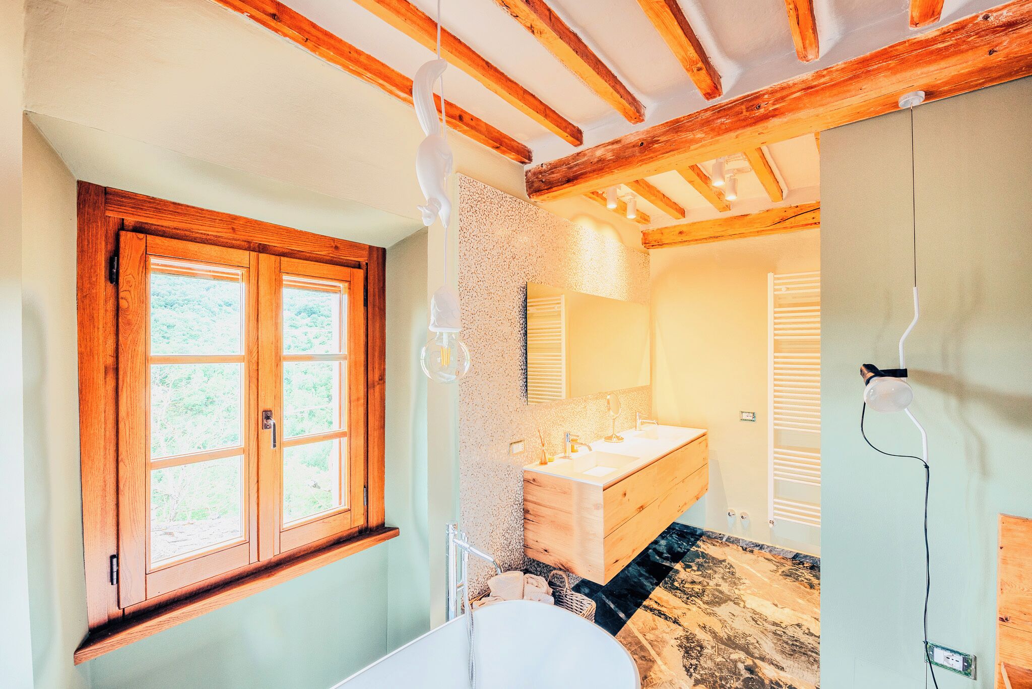 A bathroom with wooden beams, a window, a sink, and a mirror.