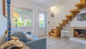 A living room with a blue sofa, a wooden coffee table, a lamp, a fireplace, and a staircase. - Villa Magnolia (Sabaudia)