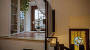 A staircase with a wooden handrail, a potted plant, and a window with a view of the outside. - Al Vicoletto (Sezze)