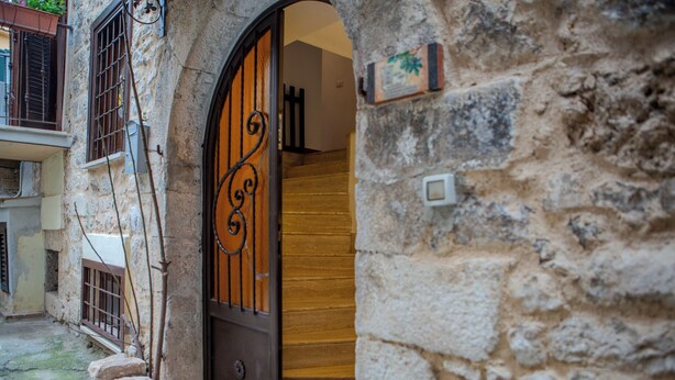 A stone building with a wooden door and a metal gate. - Al Vicoletto (Sezze)