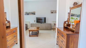 A living room with a TV, wooden furniture, and cityscape artwork on the walls. - Casa Carmen (Capaccio-Paestum)