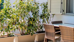 An outdoor patio with potted plants, wicker chairs, and a table. - Casa Carmen (Capaccio-Paestum)