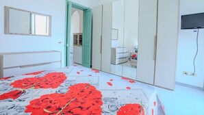 Un dormitorio con cama, armario, espejo y televisor.