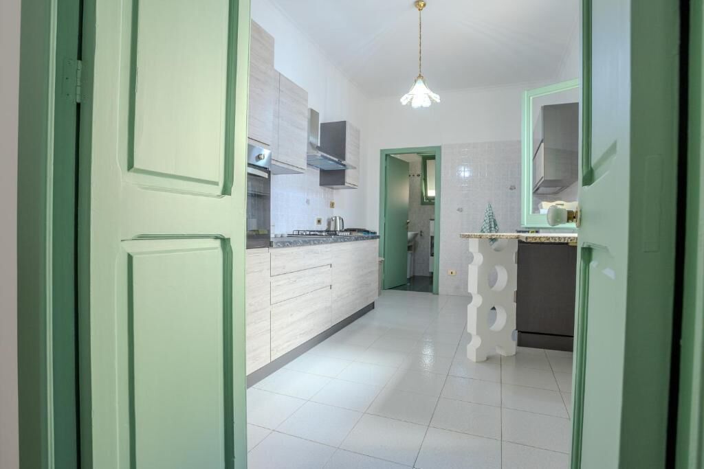 Una cocina moderna con armarios blancos, una isla central y una lámpara colgante.