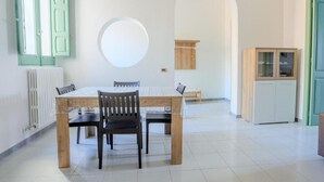 Un comedor con una mesa redonda, sillas, un radiador y un armario.