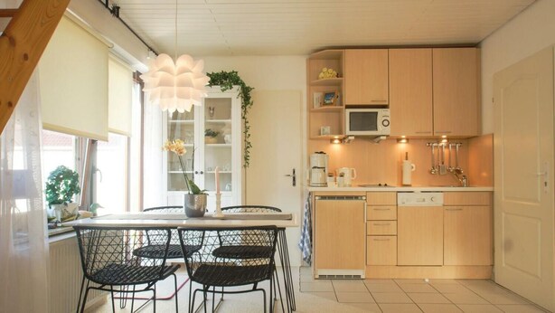 Una cocina compacta con mesa, sillas y electrodomésticos básicos.