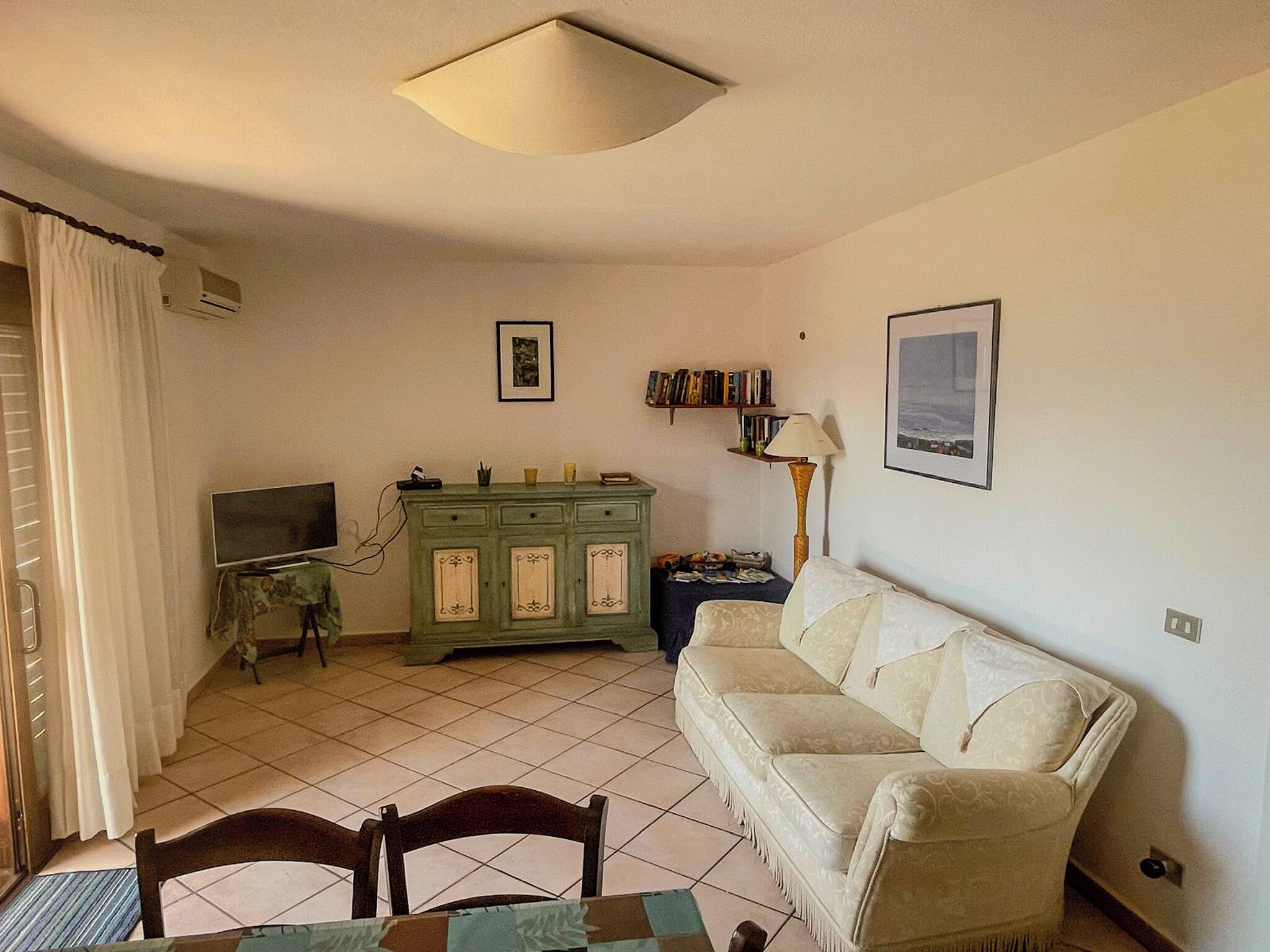 A living room with a sofa, a television, a cabinet, and a lamp.